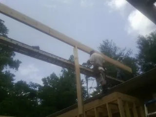 Carpenter setting a ridge beam over a new addition frame — Ice Dam Removal by Roofing Brothers in Niles