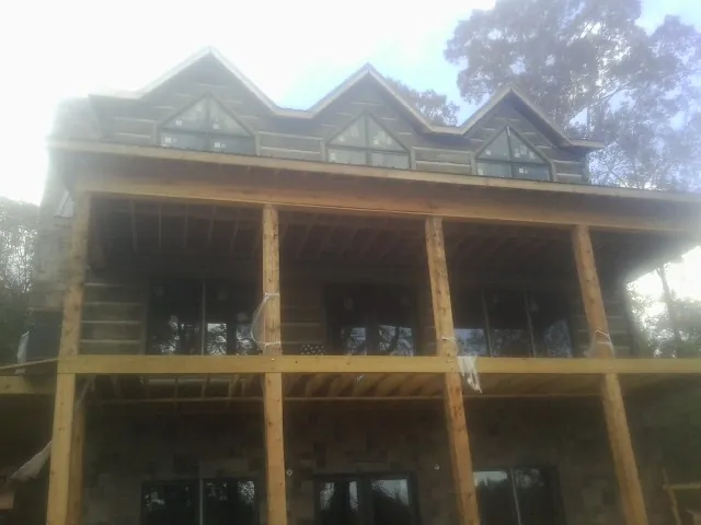 Dormers and porch framing on a large log home under construction — Roof Coating work by our crew in Niles